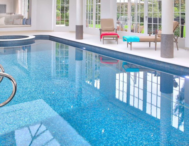 A classic style indoor Falcon Pool with metal pool ladder and built in spa pool